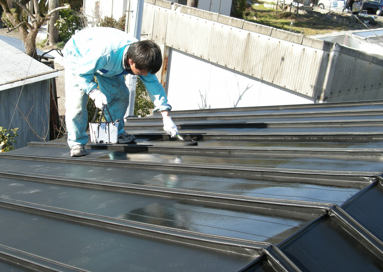 屋根の塗装する作業員